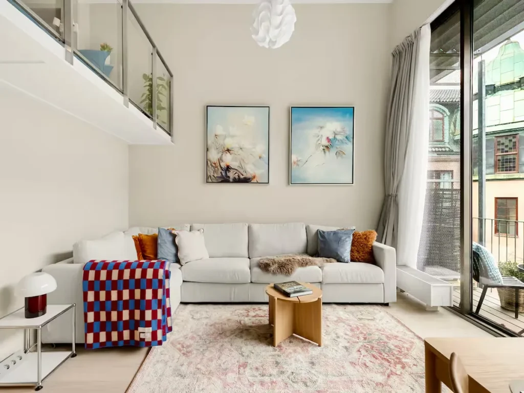 Bright, cozy modern vacation rental living room opens to an empty balcony, offering a serene off-season city escape.