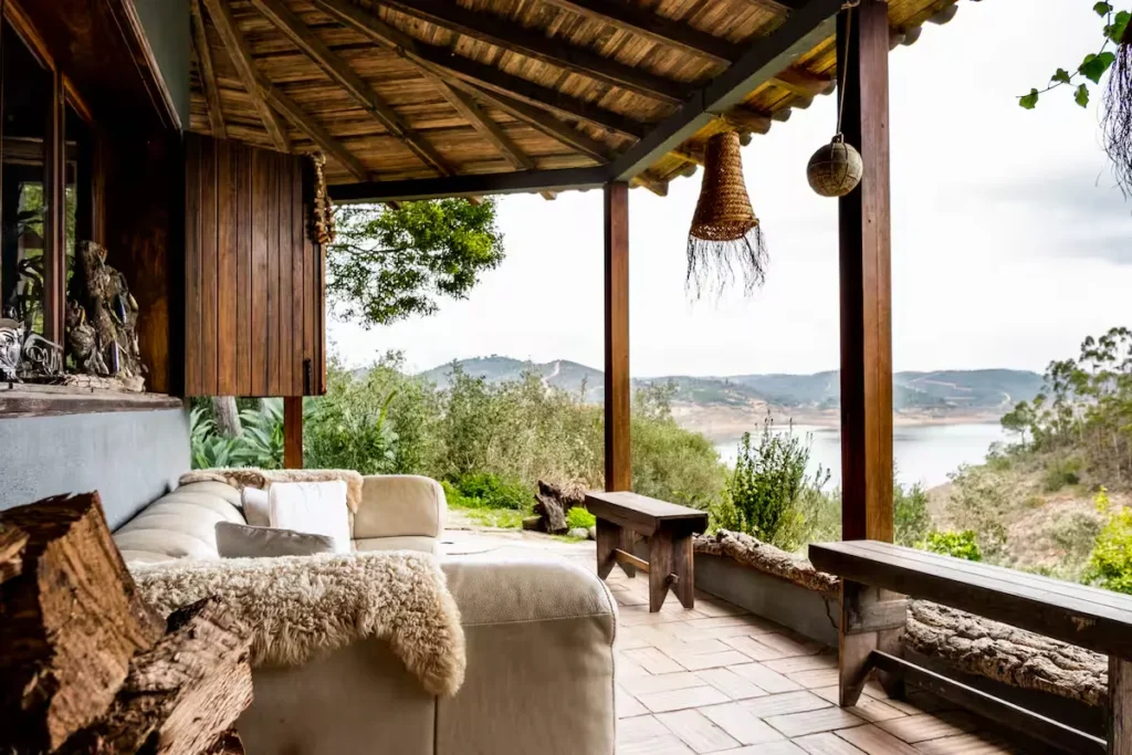 Cozy lakeside retreat terrace with empty fleece sofa and wooden benches overlooking misty hills in off-season calm