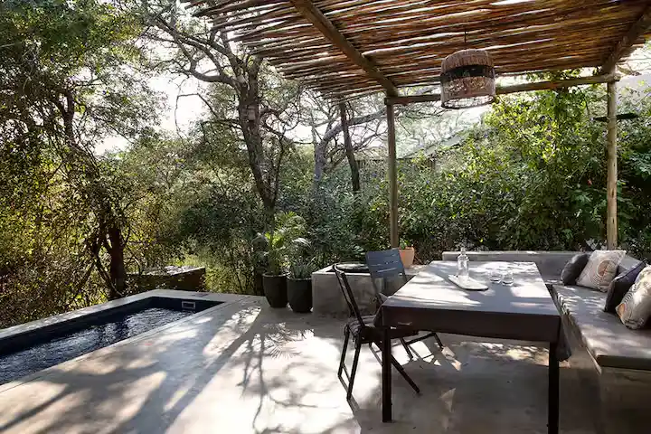 Secluded off-season lodge terrace with private plunge pool, shaded dining under rustic pergola amid lush forest canopy.