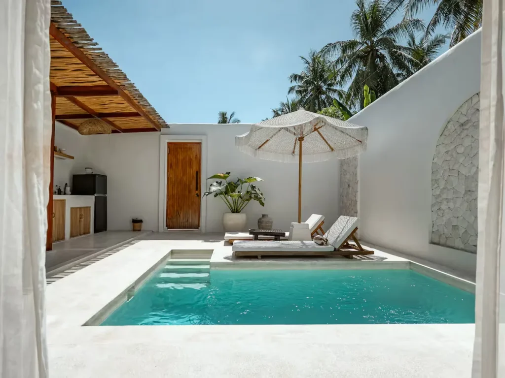 Quiet tropical villa courtyard with private turquoise pool and sun loungers, off-season luxury getaway vibe