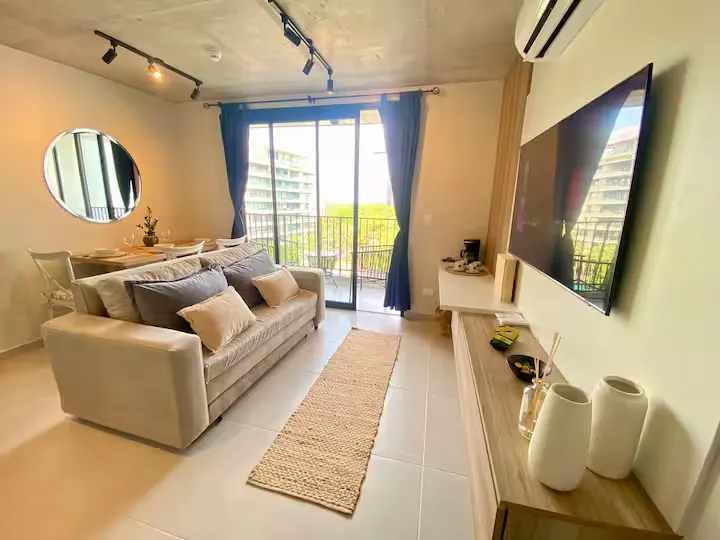 Bright modern vacation rental living room with cozy sofa and empty balcony, off-season calm, serene travel retreat vibe.