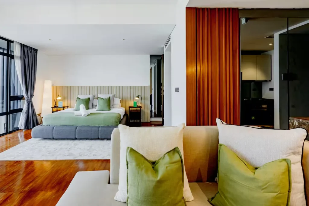 Bright modern hotel suite interior with green accents, sunlit floor-to-ceiling windows, tranquil off-season travel vibe.