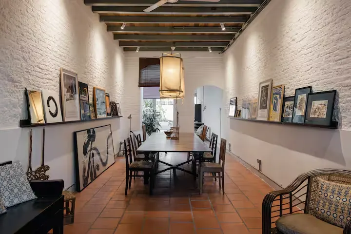 Empty rustic dining room with wooden beams, terracotta tiles and gallery-style art shelves, off-season travel serenity