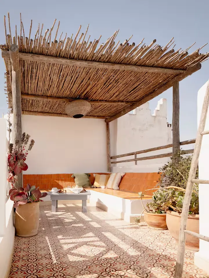 Cozy rooftop terrace with patterned tile floor and rustic pergola, quiet off-season lounge with cushions and potted plants