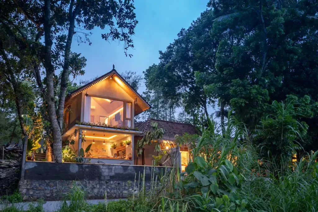 Secluded two‐story jungle lodge at dusk, glowing warmly amidst lush greenery, evoking a peaceful off‐season tropical retreat.
