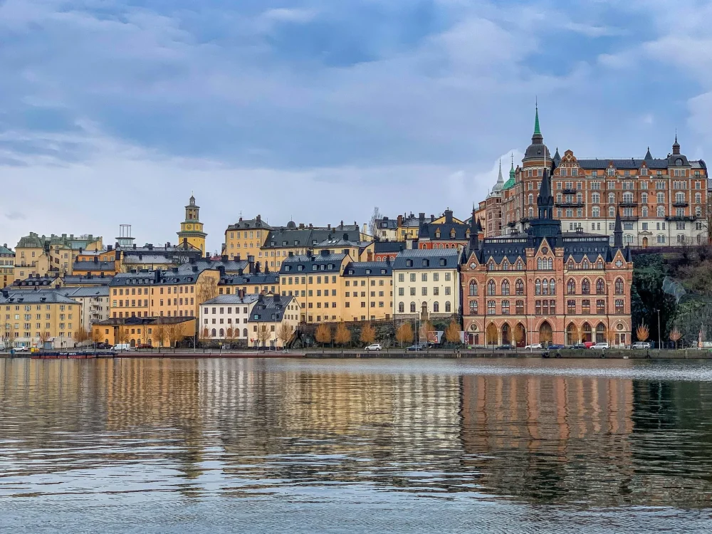 A colorful city skyline with historical buildings reflected in a calm body of water.