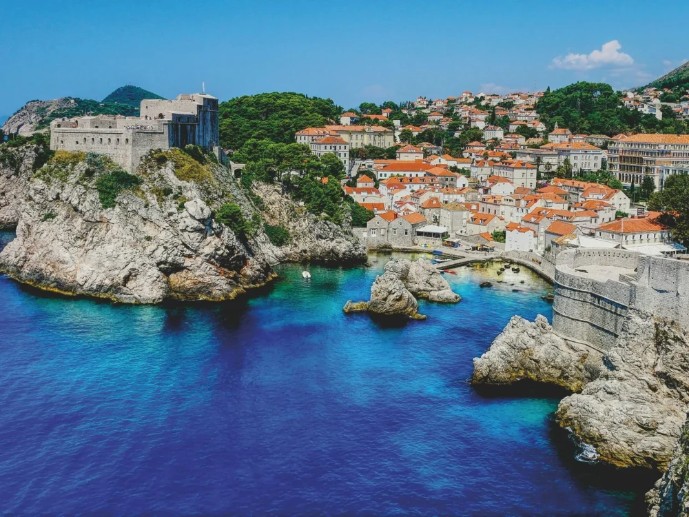 A beautiful coastal town with red-tiled roofs nestled along a vibrant blue sea.