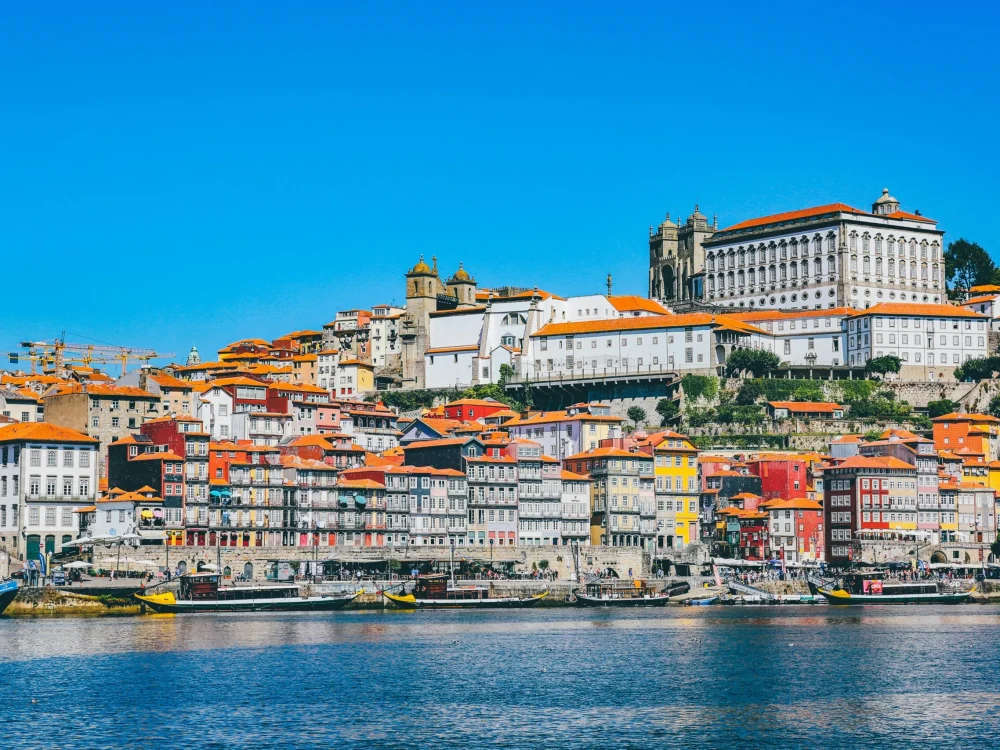 A vibrant hillside city overlooking a river, with colorful buildings cascading down to the water.